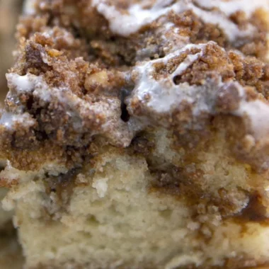 Delicious homemade coffee cake on a plate with a steaming cup of coffee
