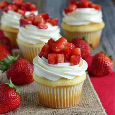 Strawberry shortcake cupcakes topped with fresh strawberries and whipped cream