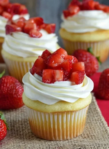 Strawberry shortcake cupcakes topped with fresh strawberries and whipped cream