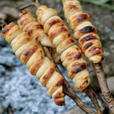 Homemade Campfire Bread cooking over an open flame outdoors