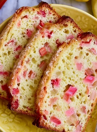 Slices of classic lemon rhubarb bread on a wooden cutting board.
