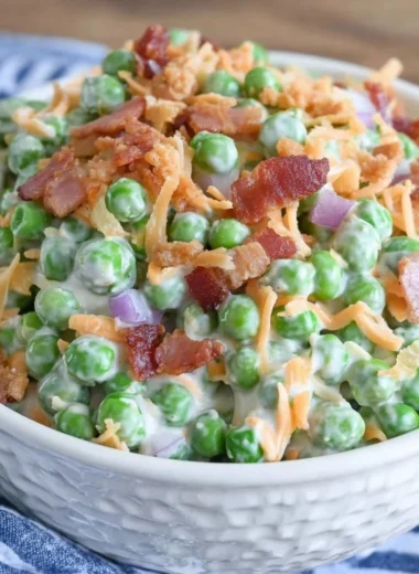 Classic pea salad with bacon served in a bowl, garnished with herbs.
