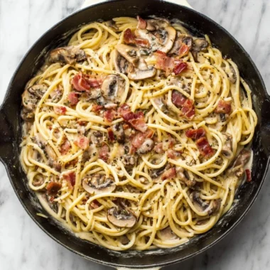 Creamy bacon mushroom pasta dish garnished with parsley on a plate