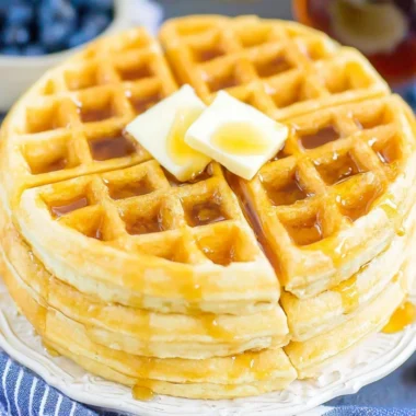 Fluffy Belgian waffles served with syrup and berries on a plate