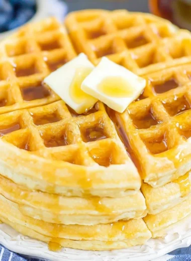Fluffy Belgian waffles served with syrup and berries on a plate