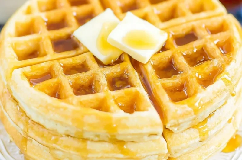 Fluffy Belgian waffles served with syrup and berries on a plate
