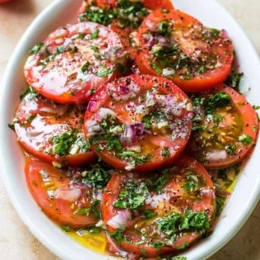 Plate of flavorful marinated tomatoes with herbs and spices.