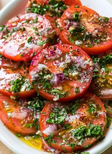 Plate of flavorful marinated tomatoes with herbs and spices.
