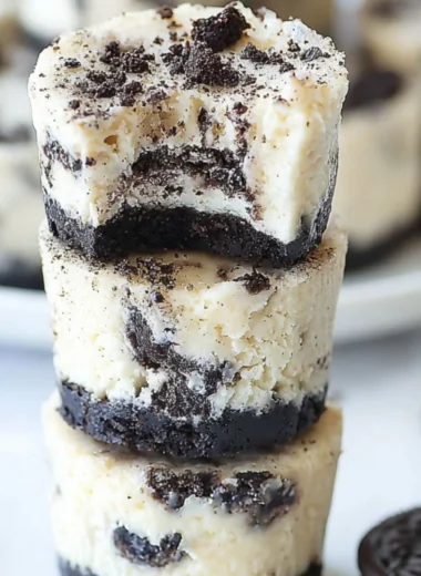 Mini Oreo Cheesecakes topped with crushed Oreos on a cookie crust.