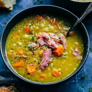 Bowl of homemade Split Pea Soup garnished with herbs and served with bread.