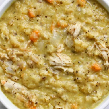 A bowl of cauliflower chicken soup garnished with herbs and vegetables