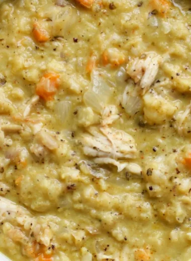 A bowl of cauliflower chicken soup garnished with herbs and vegetables