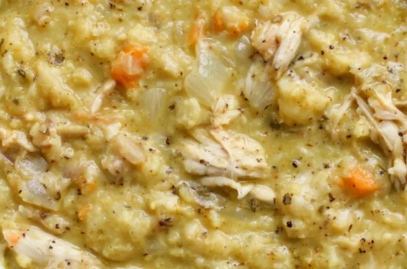 A bowl of cauliflower chicken soup garnished with herbs and vegetables