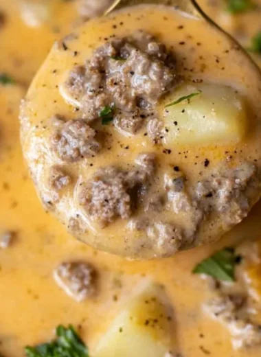 Bowl of Cheesy Beef and Potato Soup garnished with fresh herbs