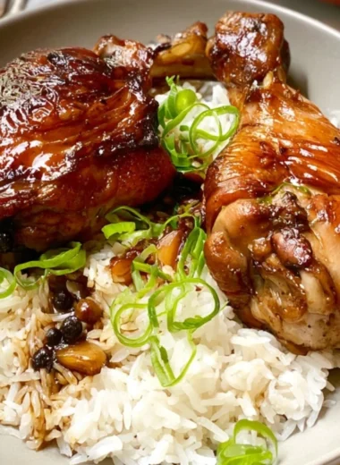 Delicious Chicken Adobo served in a bowl with rice and garnished with herbs.