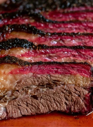 Smoked beef chuck roast on a cutting board garnished with herbs