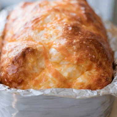 Freshly baked sourdough cheese bread with a golden crust and gooey cheese inside.