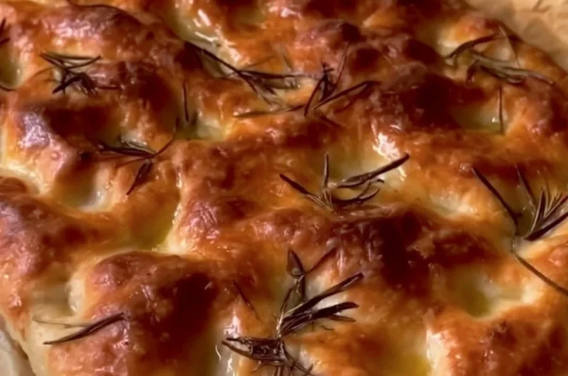 Delicious homemade sourdough focaccia bread topped with herbs and olive oil.